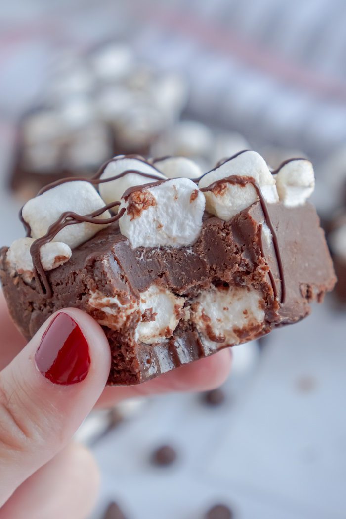 A hand holding a piece of chocolate fudge with marshmallows.
