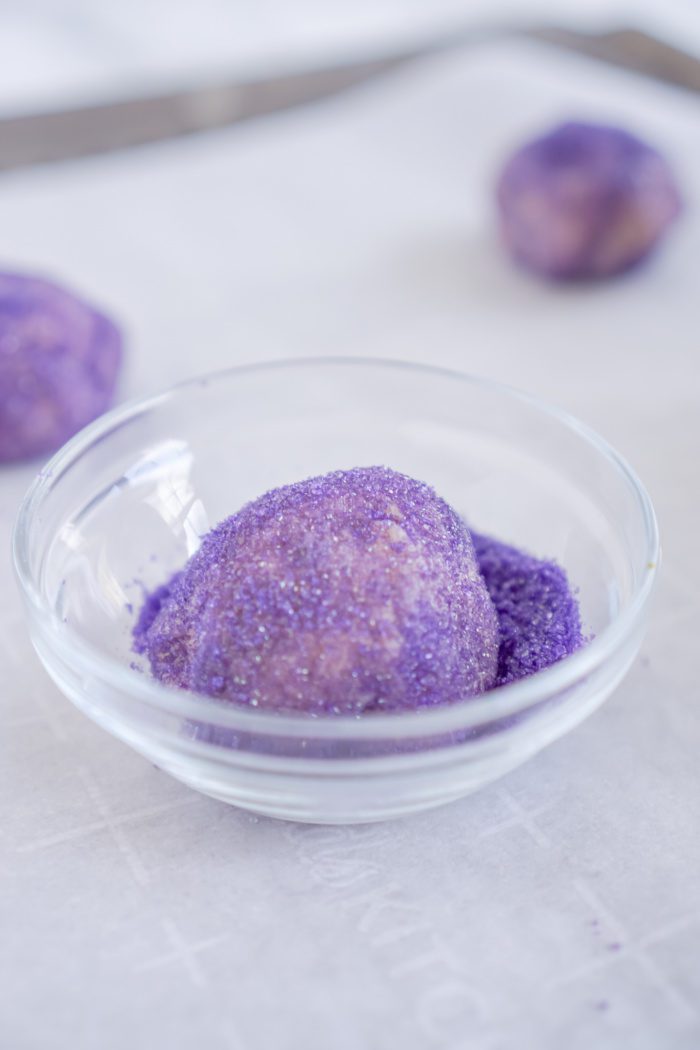 A purple cookie dough ball in a glass bowl.