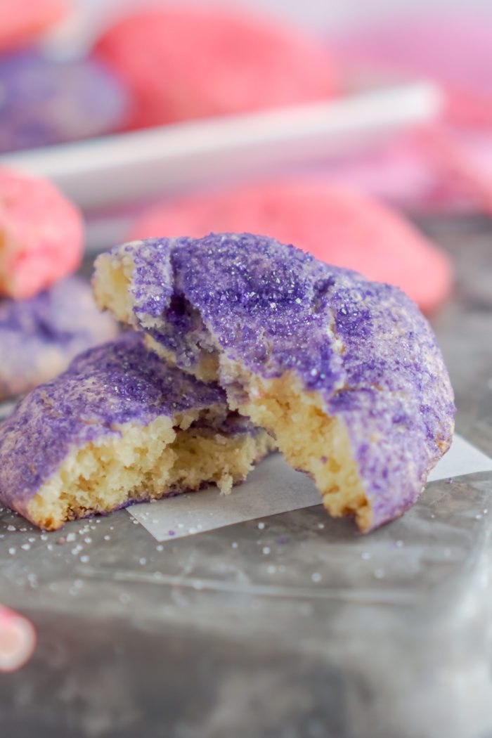 A close-up image of a purple sugar cookie broken in half.