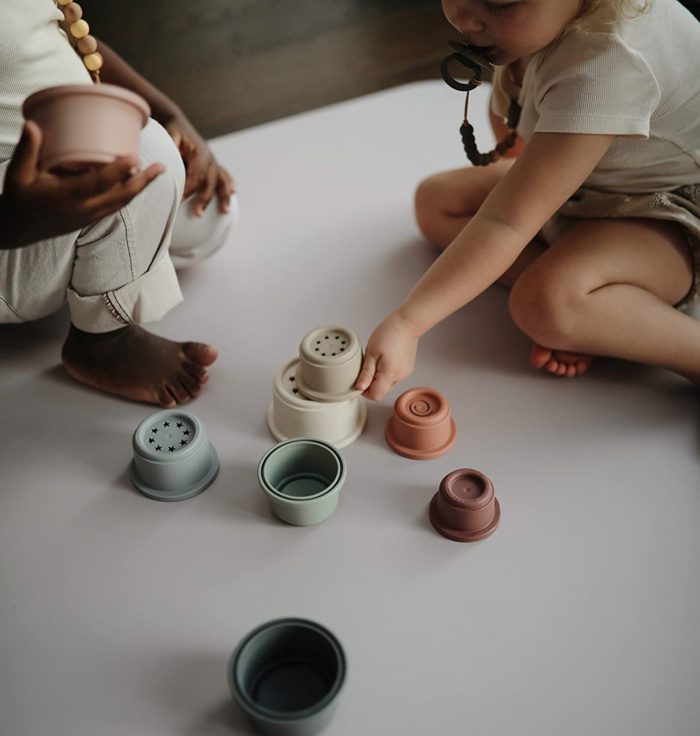 Two toddlers play with a stacking toy.