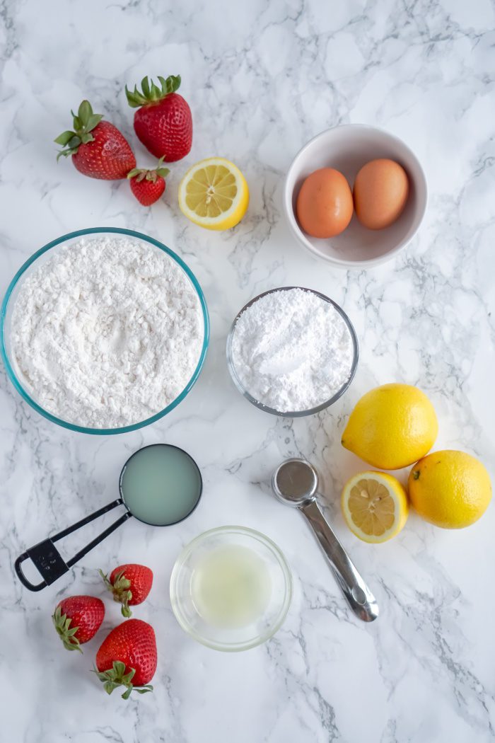Ingredients for strawberry lemon cake on marble table.