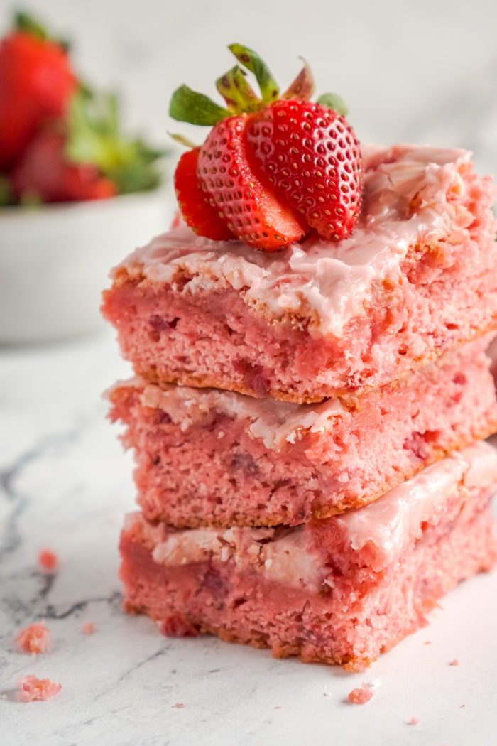 A stack of three strawberry cake slices.