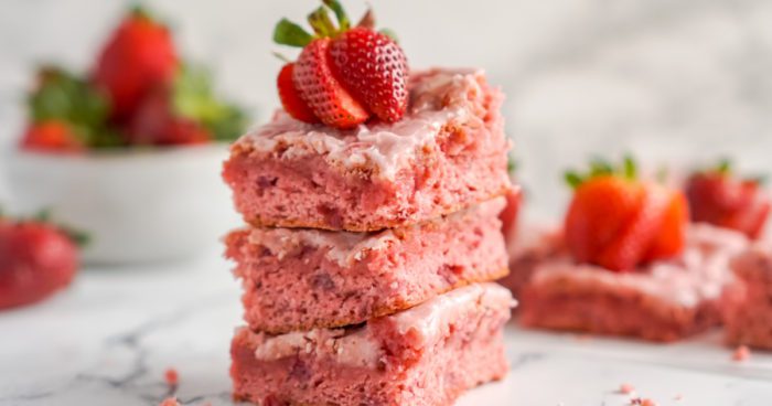 A stack of three strawberry poke cake squares.