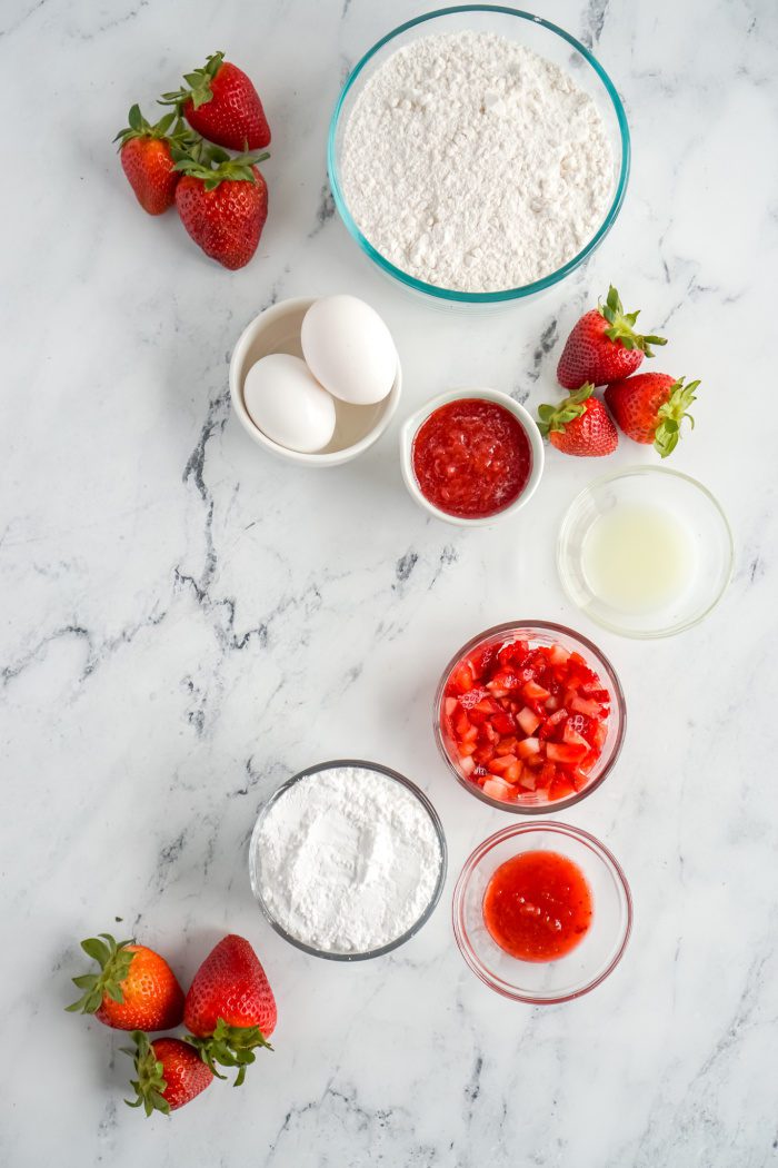 Ingredients for strawberry cake on marble table.