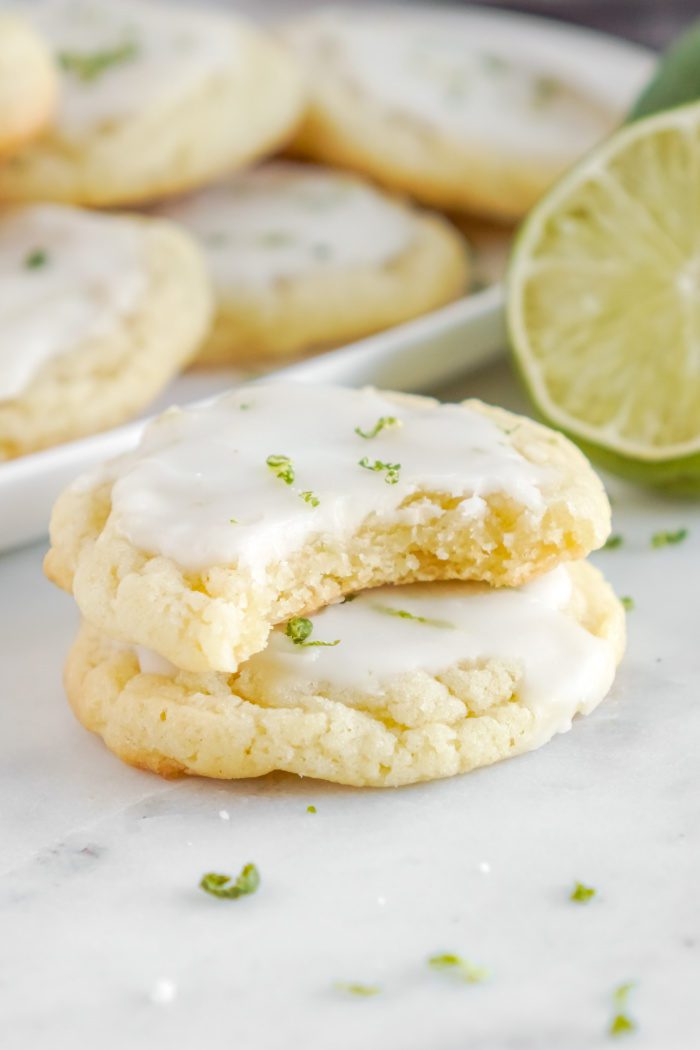 A stack of two sugar cookies with white icing and lime zest.