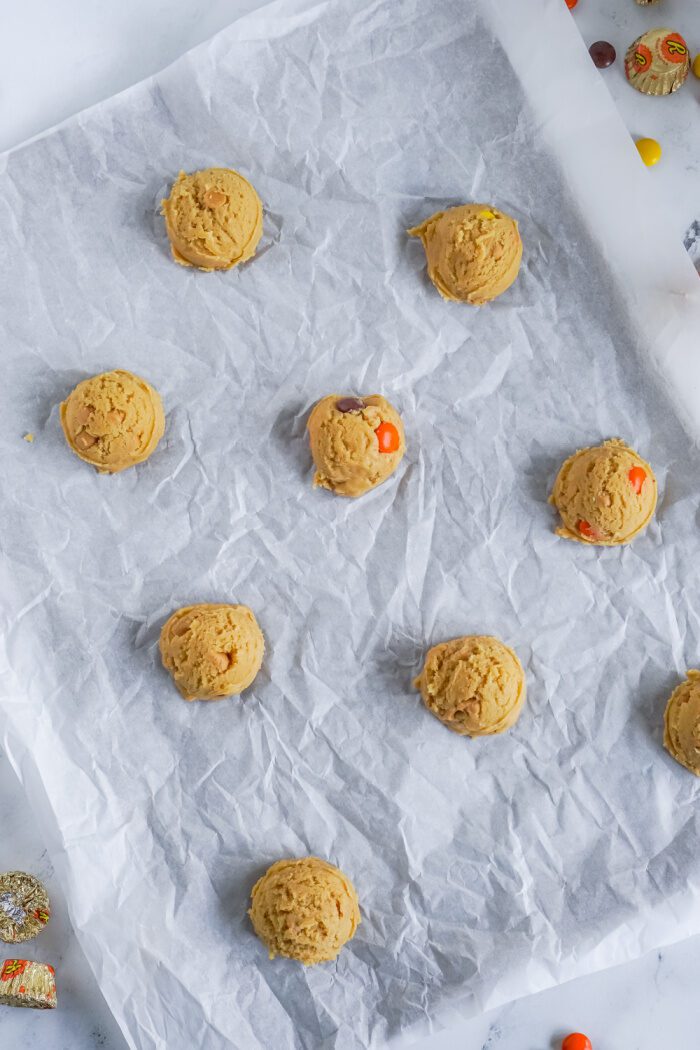 Peanut butter cookie dough balls on parchment paper.