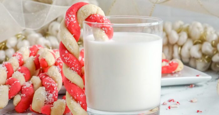 Wide view of cookie hanging of the side of a glass of milk