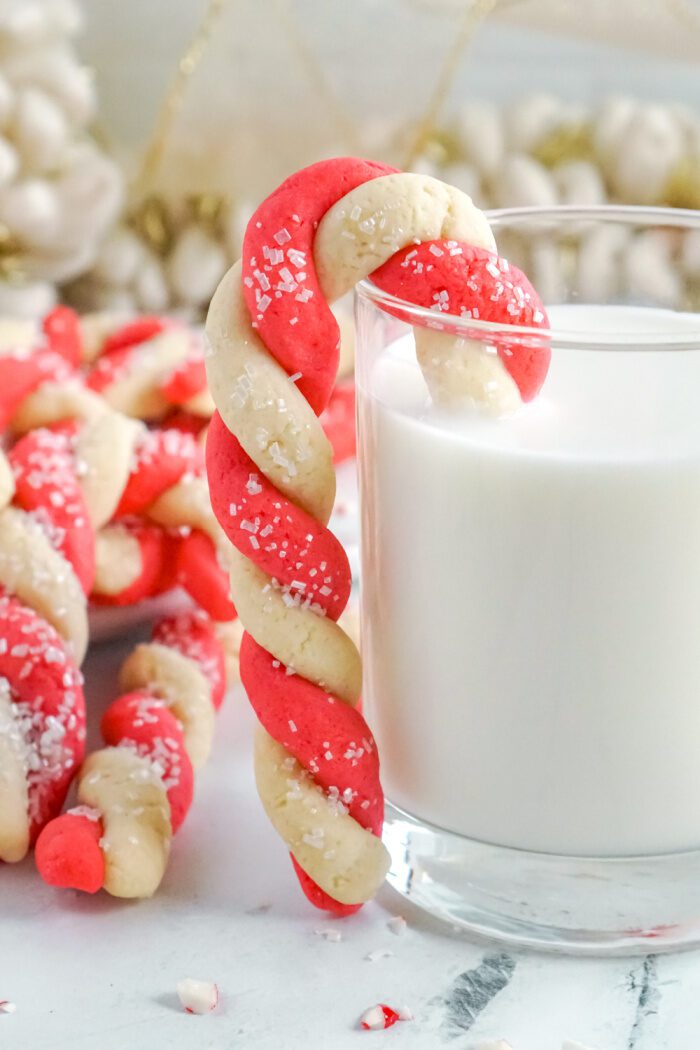 Candy Cane Sugar Cookie Hooked Onto Side of Milk Glass