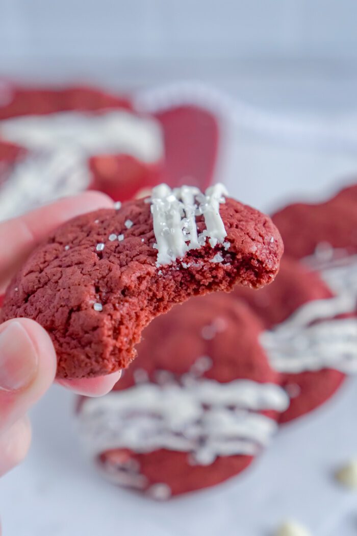 Someone Holding a Red Velvet Cookie With a Bite Taken Out