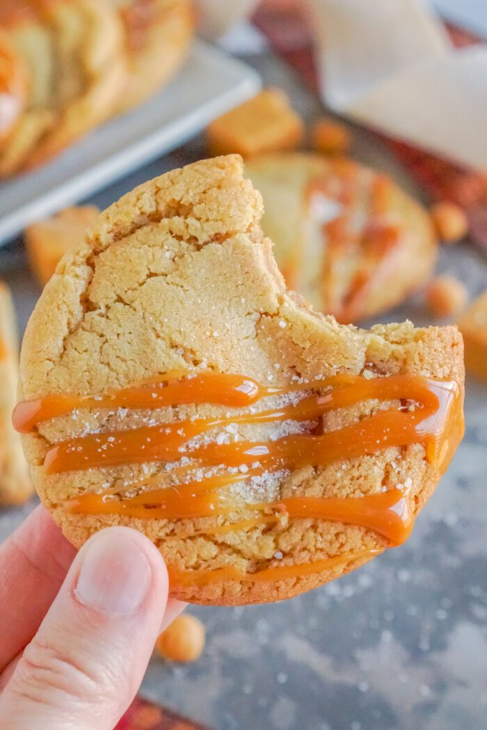 Someone Holding a Salted Caramel Cookie With a Bite Taken Out