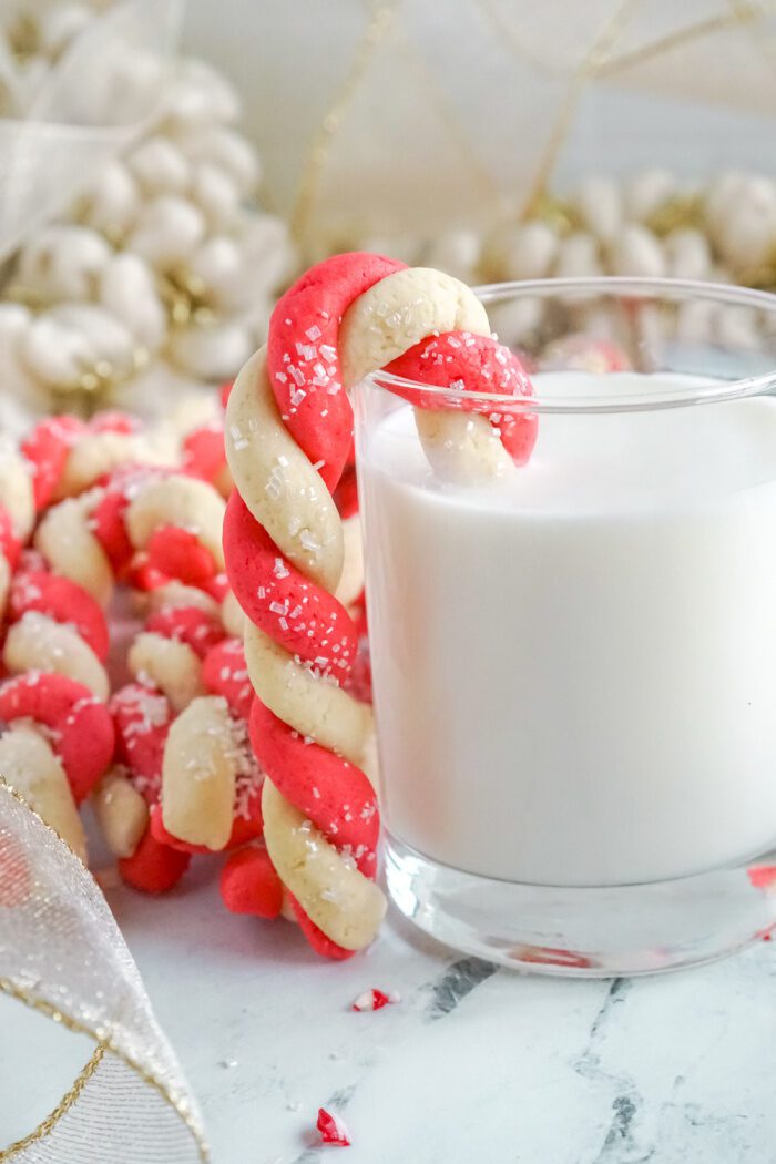 Candy Cane Sugar Cookie Hooked Onto the Side of Glass of Milk