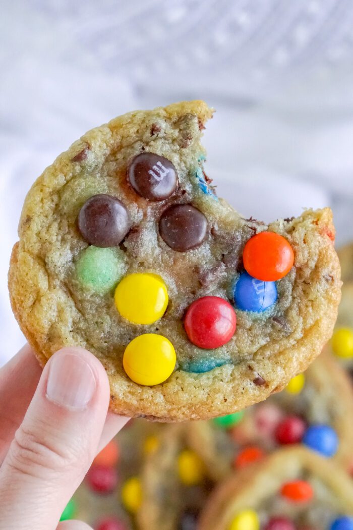 Close Up View of Someone Holding a M&M Cookie With Bite Taken Out