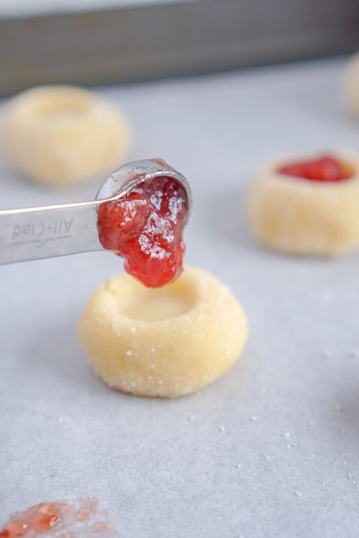 Pouring jam in hole of cookie dough ball