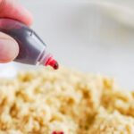 Red food dye being added to cookie dough