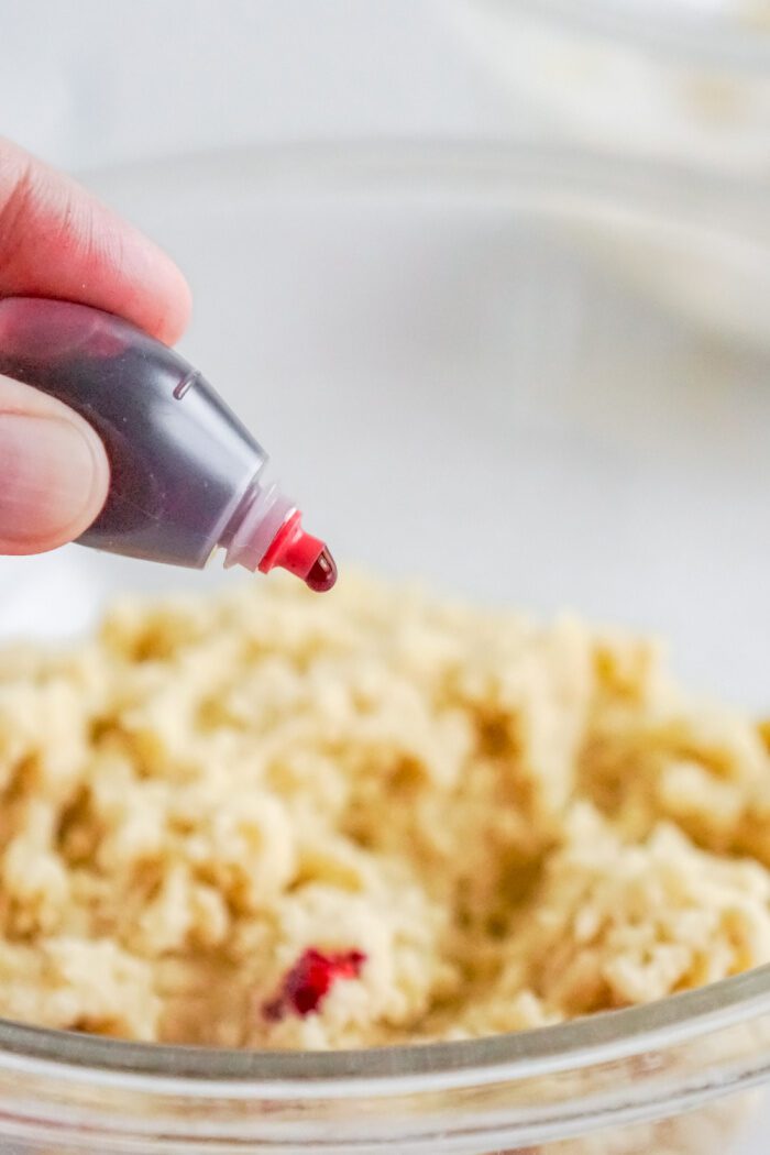 Red food dye being added to cookie dough