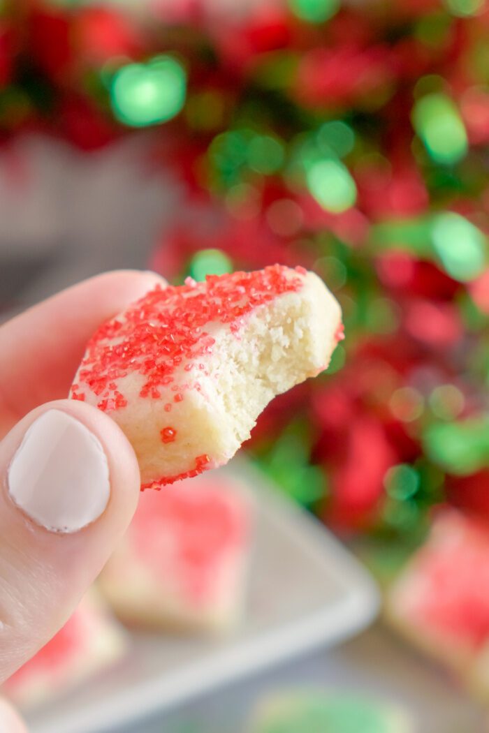 Someone Holding a Mini Christmas Sugar Cookie With Bite Taken Out