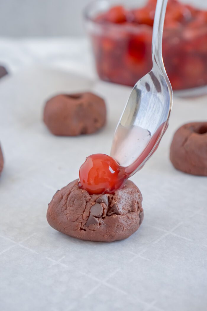 Topping cookie dough ball with cherry