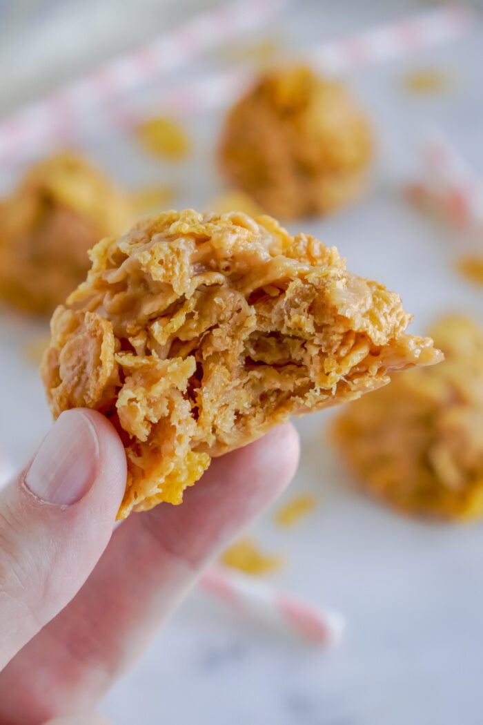 Someone Holding a Cornflake Cookie With a Bite Taken Out