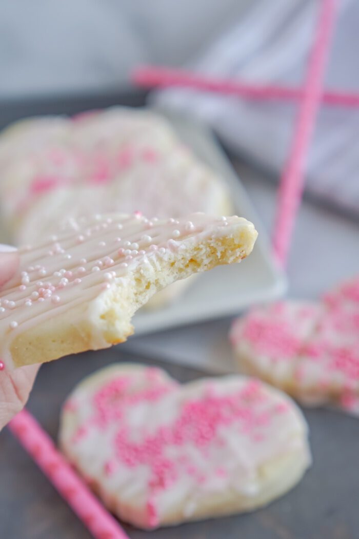 Someone Holding A Valentine's Day Cookie With A Bite Taken Out Of It