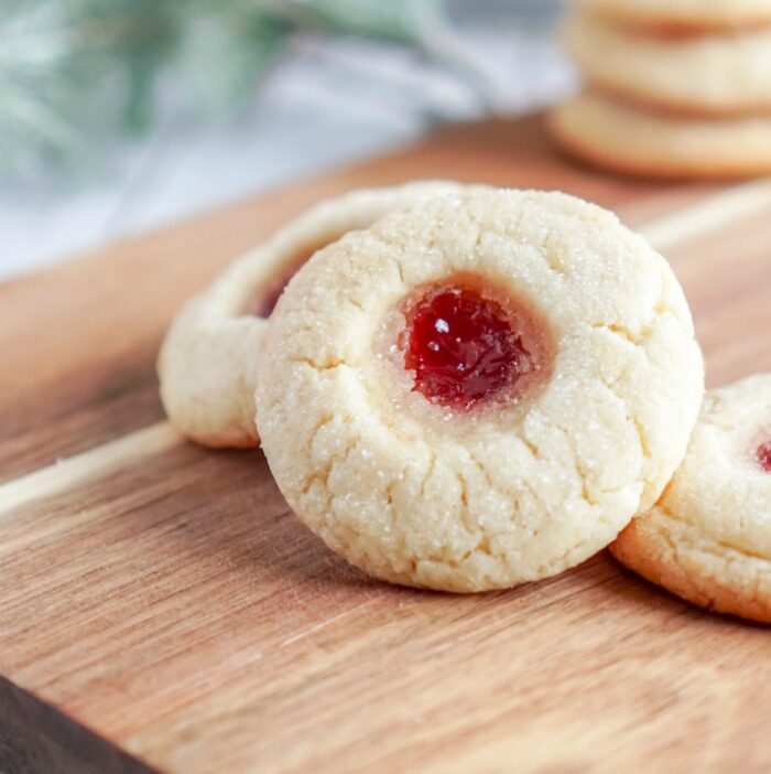 A Christmas Thumbprint Sugar Cookie propped up on another cookie