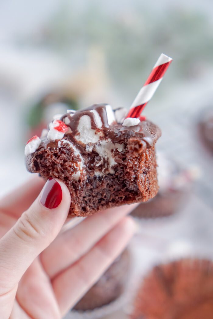 Someone holding a Hot Chocolate Cupcake with a bite taken out of it