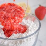 Blended strawberries being mixed in with the powdered sugar