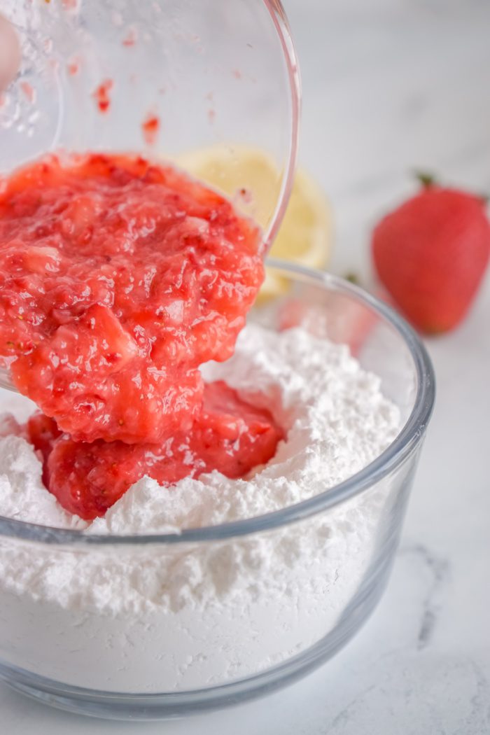 Blended strawberries being mixed in with the powdered sugar