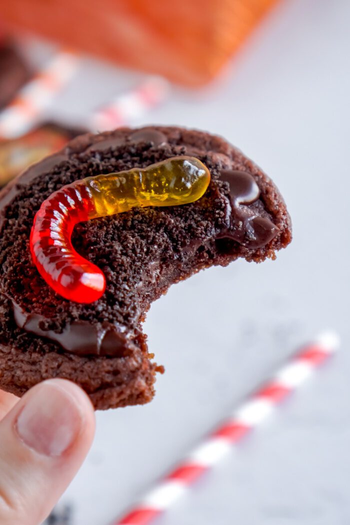 Someone holding a Oreo Dirt Pudding Chocolate Cookie with a bite taken out of it