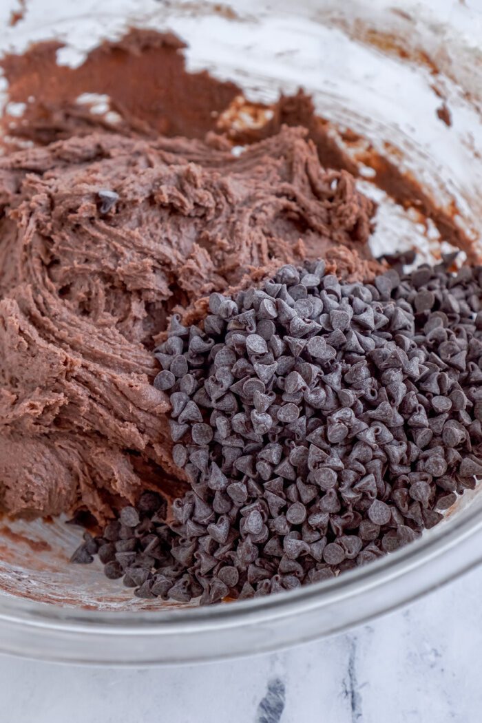 Chocolate chips being added to cookie dough