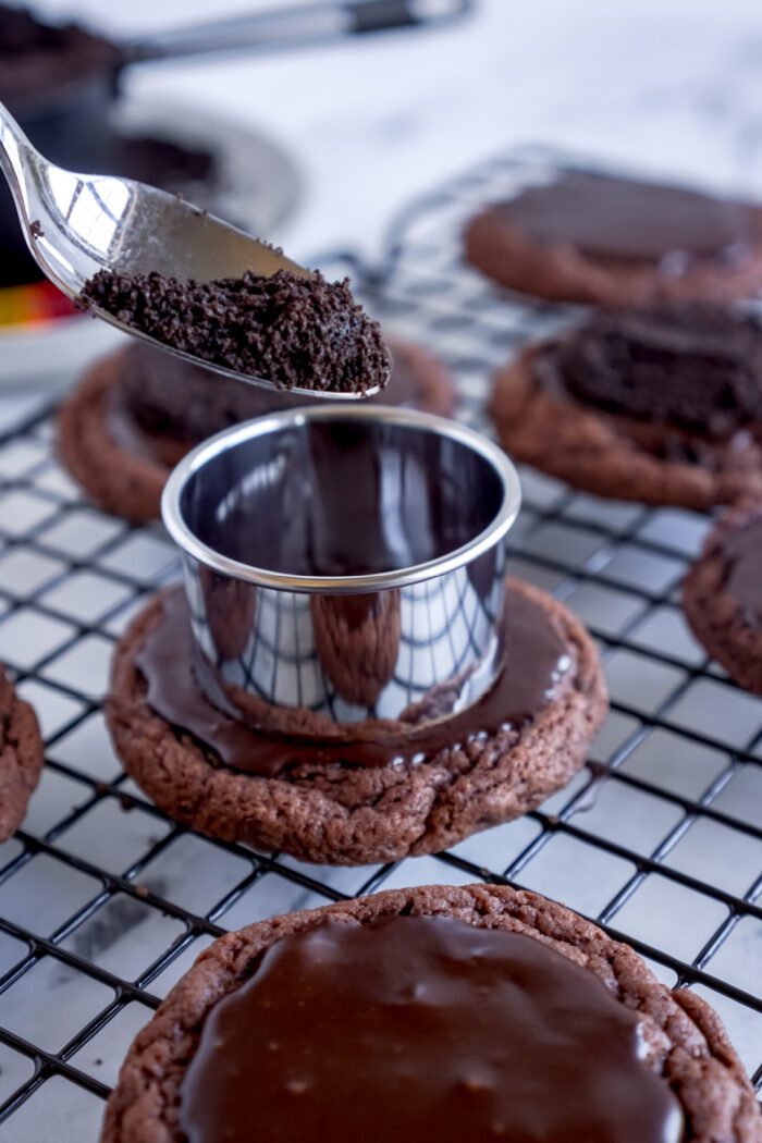 Crushed Oreos being spooned onto glazed cookie