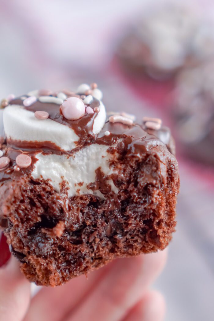 Someone holding a Valentine's Day Hot Chocolate Cupcake with a bite taken out of it