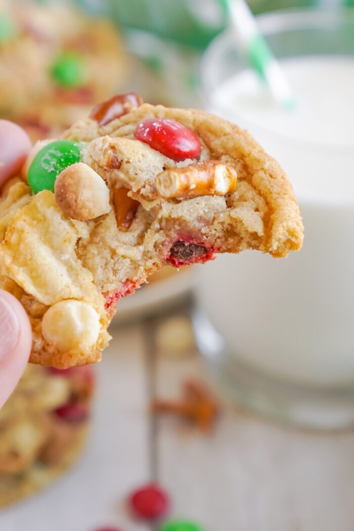 Someone holding a Kitchen Sink Christmas Cookie with a bite taken out of it