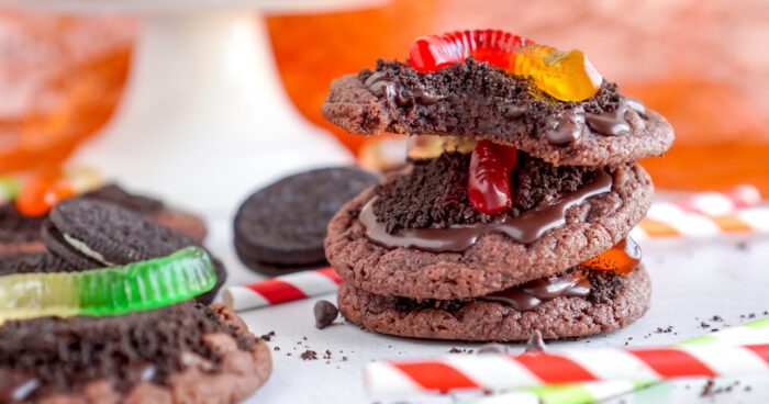 A close-up image of a stack of two chocolate cookies with gummy worms.