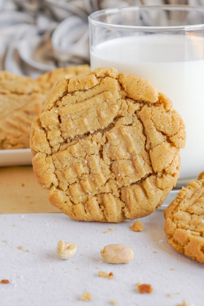 A Peanut Butter Cookie propped up on a glass of milk