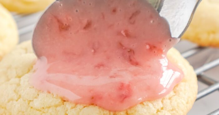 Adding strawberry glaze to sugar cookie.