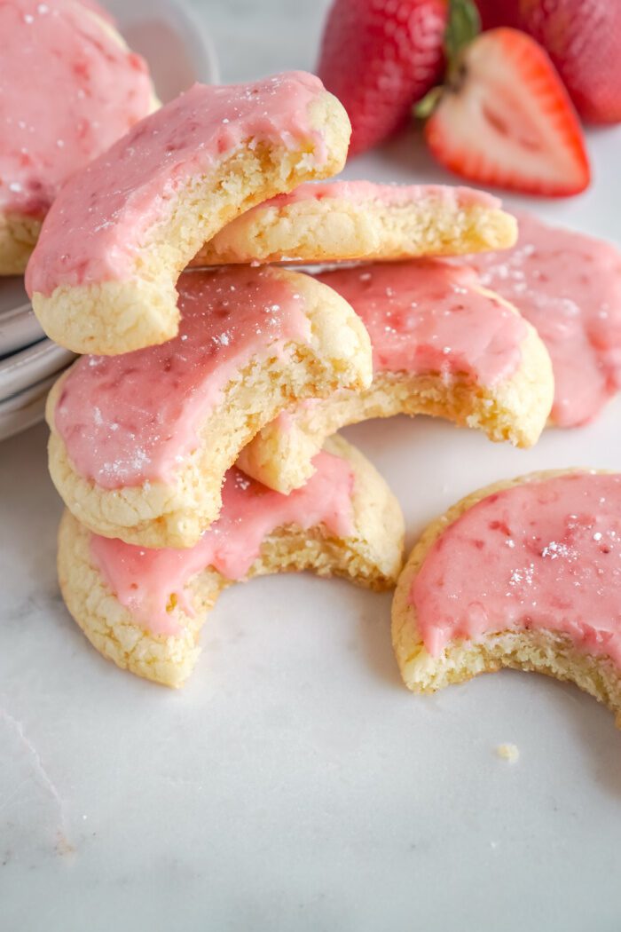 A stack of bitten strawberry sugar cookies.