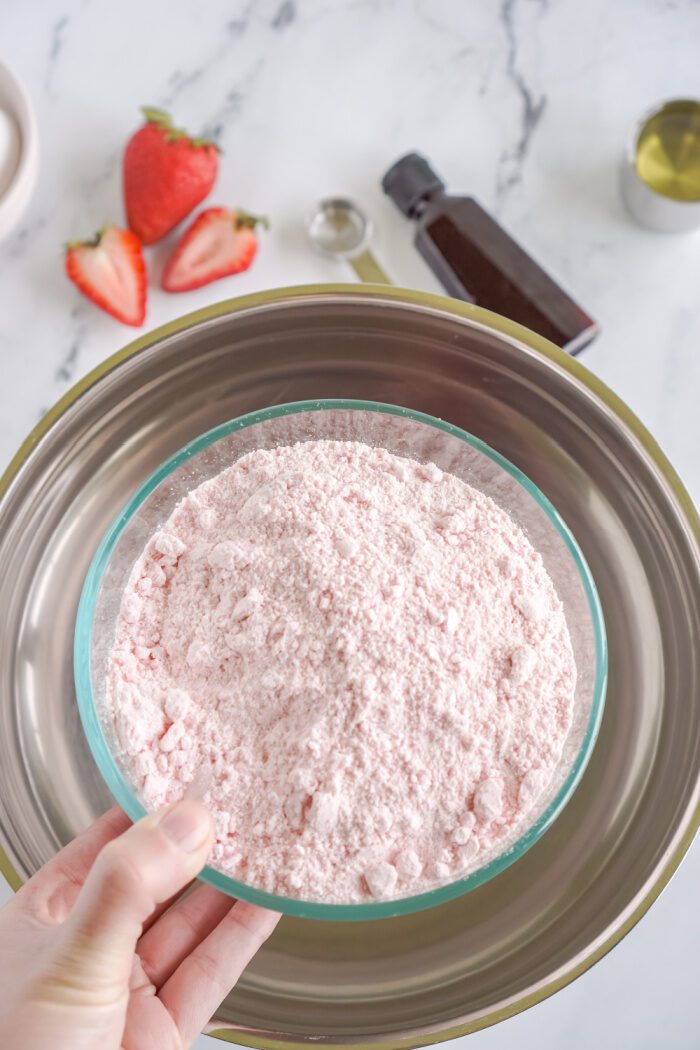 Strawberry cake mix being poured in a bowl