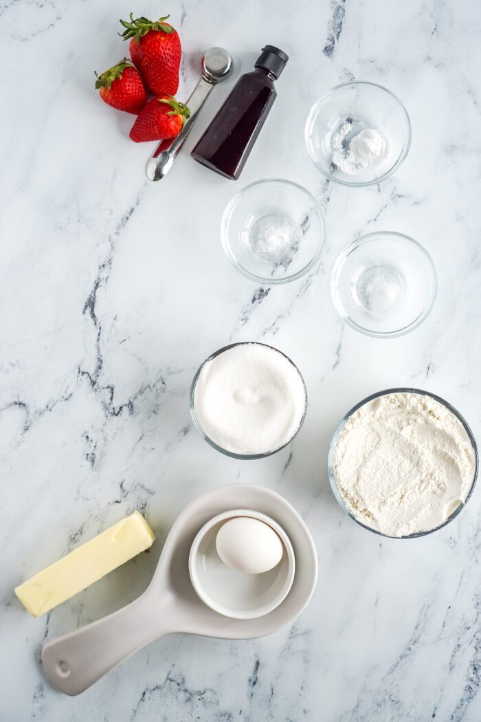 Ingredients for strawberry cake on marble table.