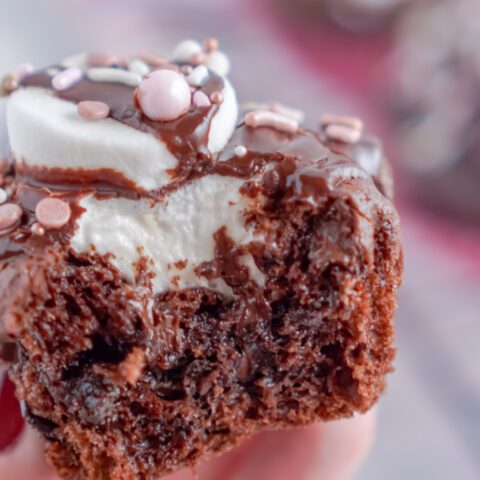 Close up view of someone holding a Valentine's Day Hot Chocolate Cupcake with a bite taken out of it