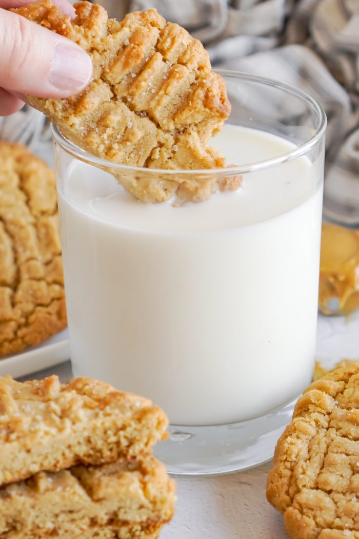 Someone dipping Peanut Butter cookie into a glass of milk