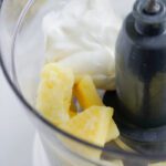 Frozen pineapple, yogurt, and ice in blender