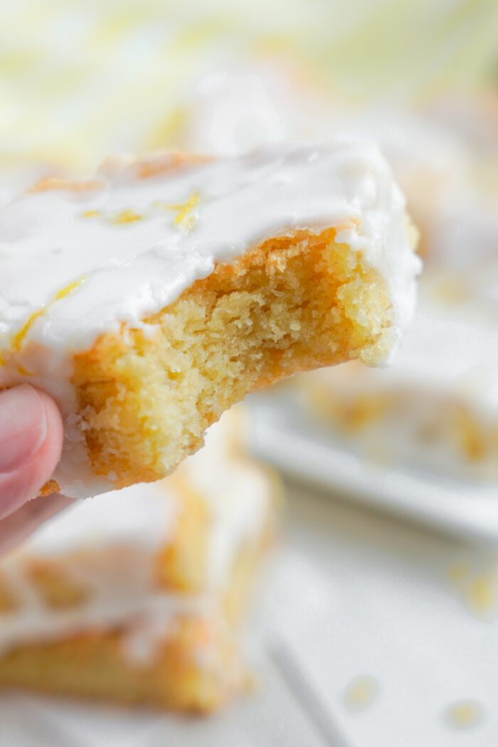 Someone holding a Lemon Sugar Cookie Bar with a bite taken out of it