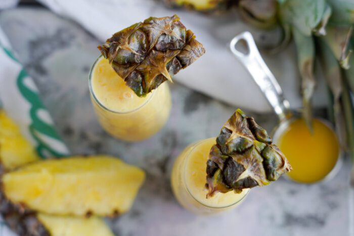 Two champagne glasses with pineapple juice and a pineapple slice.