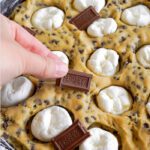 Adding marshmallows and hershey chocolate on top of cookie dough