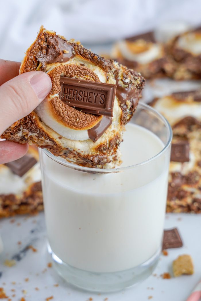 Someone dunking a S'mores Bar into a glass of milk