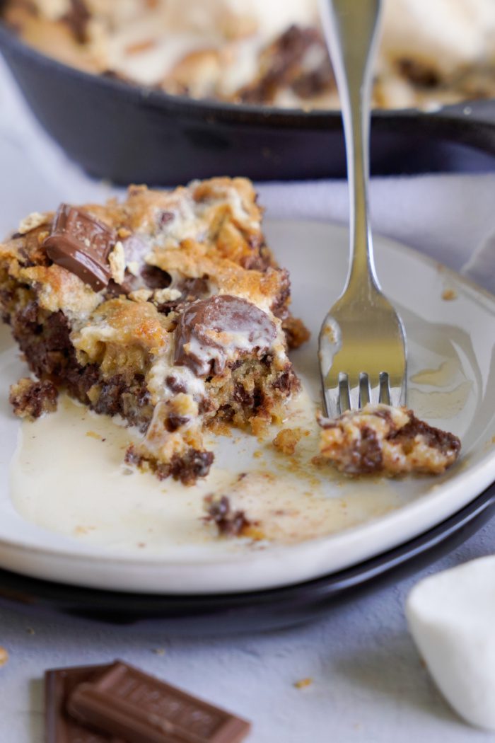 Someone taking a bite of S'mores Skillet Cookie