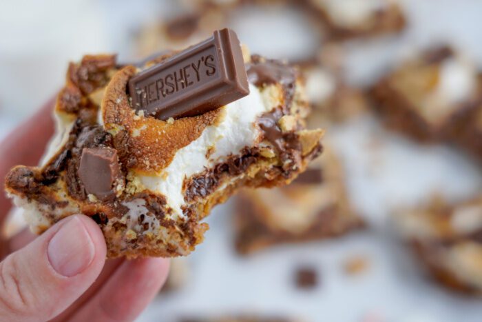 Wide view of someone holding a s'mores bar with a bite taken out of it