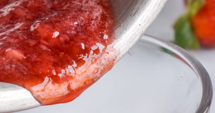 Strawberry sauce being poured from a ladle.