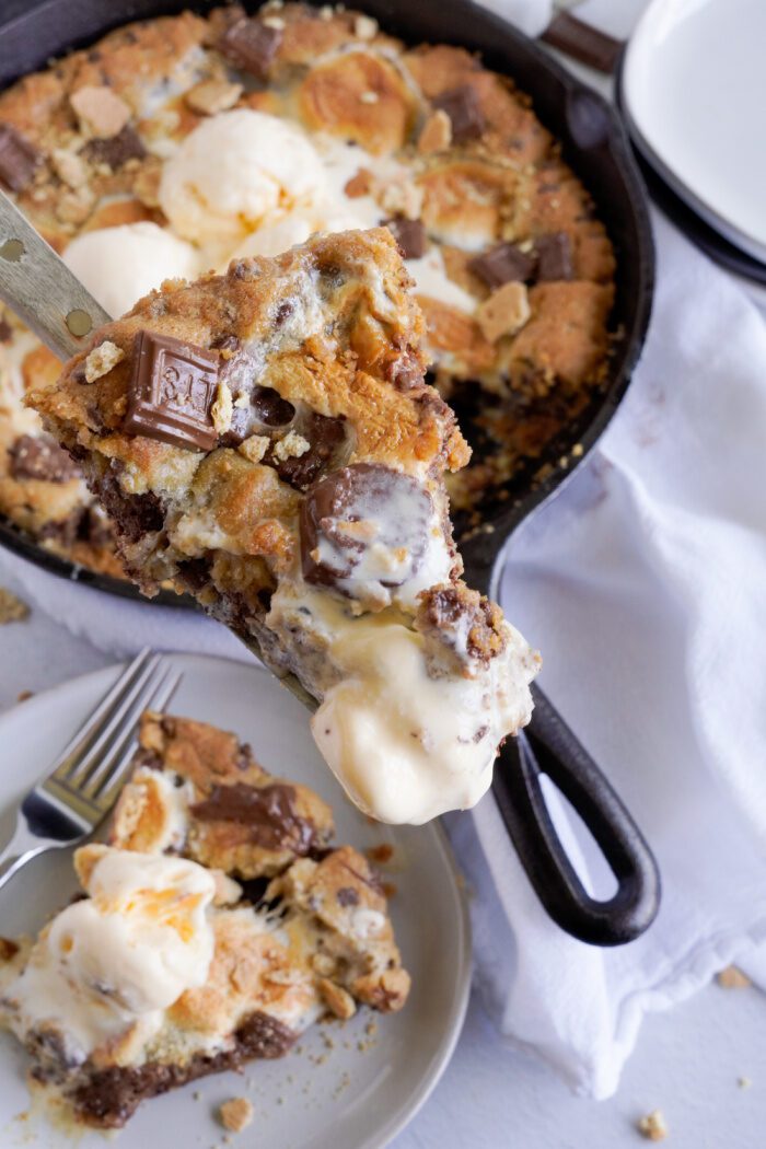 A slice of S'mores Skillet Cookie being taken out of the skillet