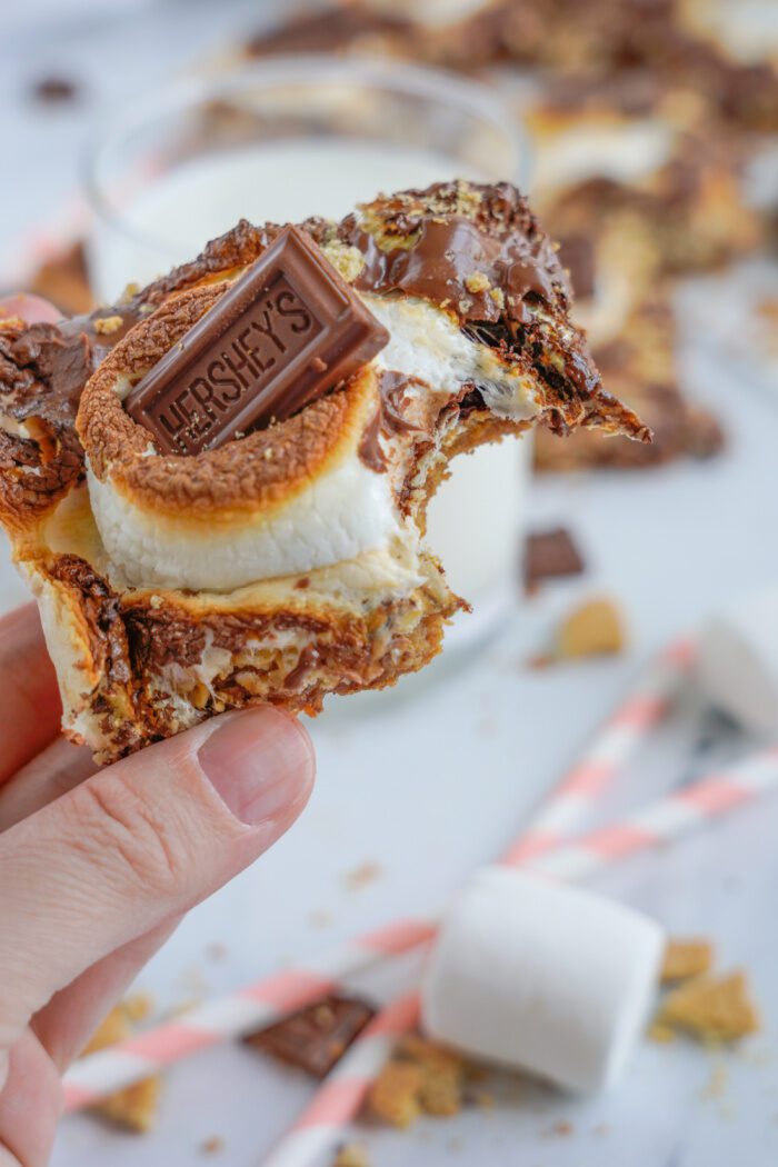 A hand holding a s'mores bar with a bitten corner.